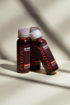 Three bottles of beetroot endurance shots with white caps on a beige background